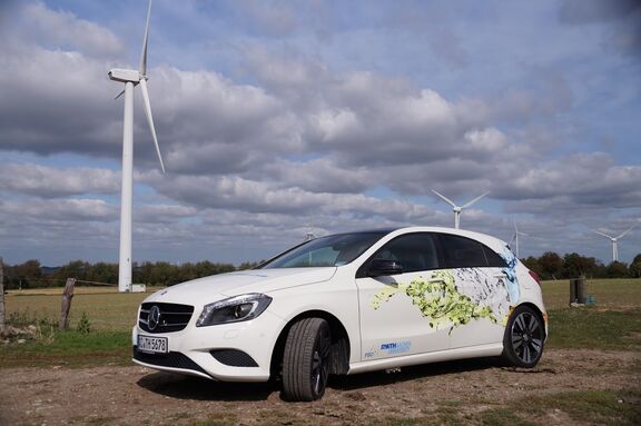 Ein stehendes Auto vor einem Feld mit Windrädern geparkt.