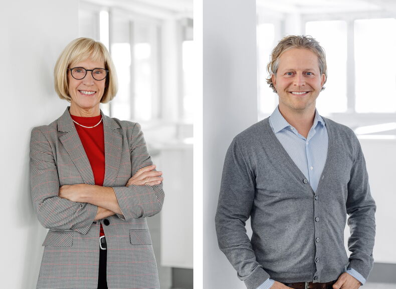 The picture is divided into two sections. On the left is head of department Geva Aschhoff. She is wearing a checked blazer and a red shirt. She is smiling at the camera. On the right is Co-Head of Department Markus Leber. He is wearing a gray cardigan and a blue-striped shirt. He has his hands in his trouser pockets and is smiling at the camera.